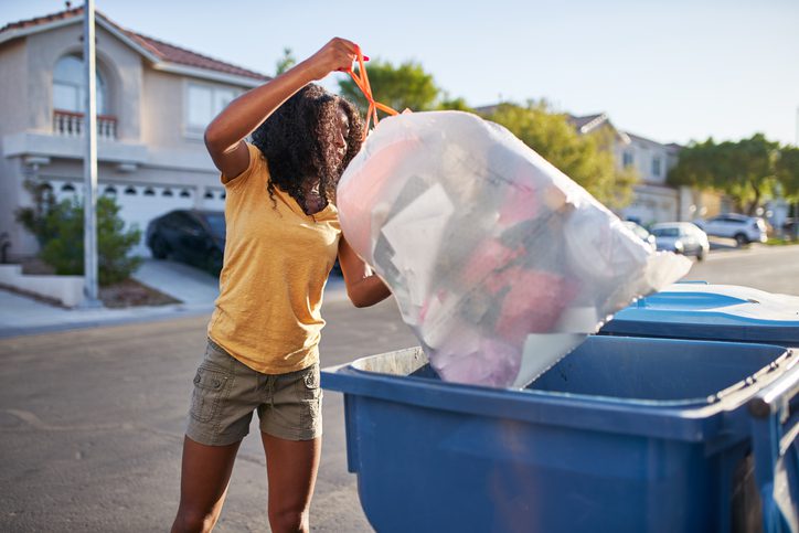 Woman placing the trash bag in the blue bin