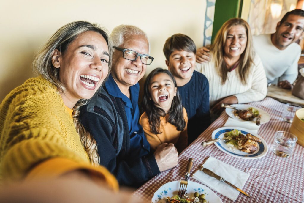 Happy latin family doing selfie while eating together at home